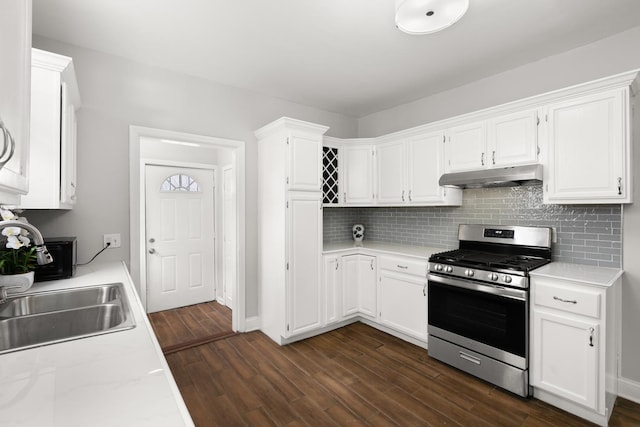 kitchen featuring gas range, under cabinet range hood, white cabinets, and dark wood-style flooring