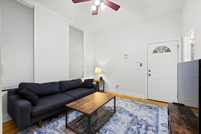 living area with a ceiling fan, baseboards, and wood finished floors