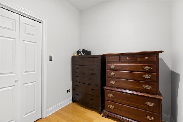 bedroom featuring light wood-type flooring, baseboards, and a closet