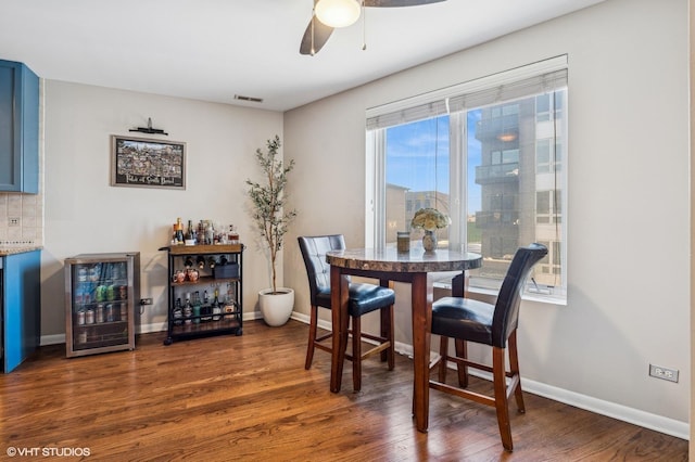 dining area with beverage cooler, visible vents, baseboards, and dark wood-type flooring