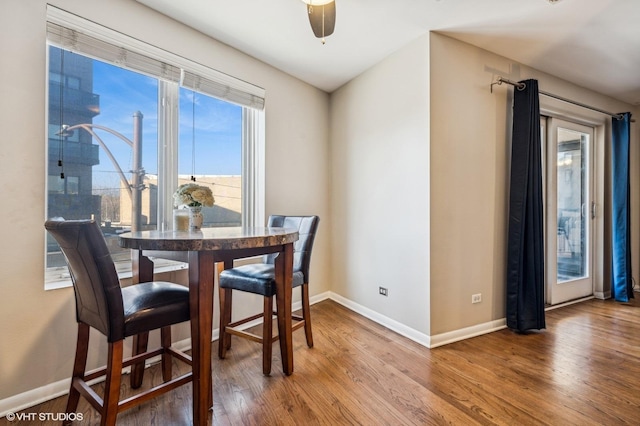 dining area with wood finished floors, a ceiling fan, and baseboards