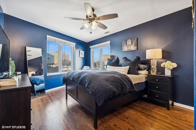 bedroom with a ceiling fan, dark wood-style flooring, visible vents, and baseboards