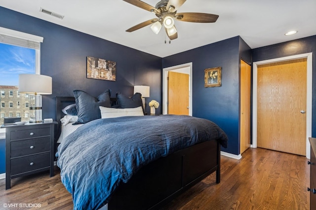 bedroom with ceiling fan, dark wood-type flooring, visible vents, and baseboards