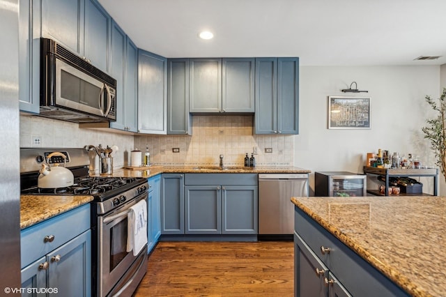 kitchen featuring dark wood-style flooring, visible vents, decorative backsplash, appliances with stainless steel finishes, and a sink