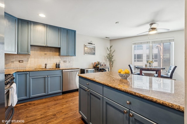 kitchen with dark wood-style flooring, recessed lighting, backsplash, appliances with stainless steel finishes, and a sink