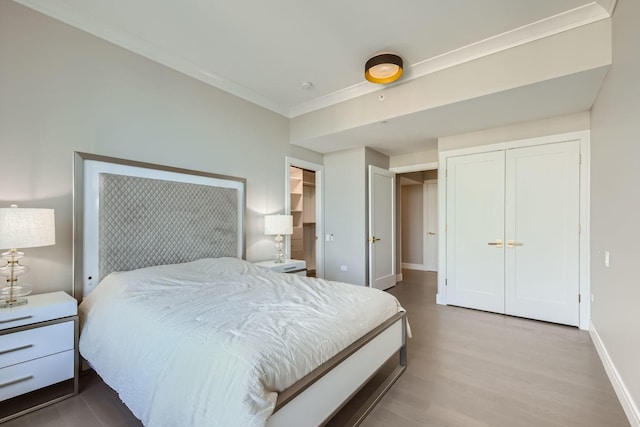 bedroom featuring multiple closets, light wood-type flooring, crown molding, and baseboards