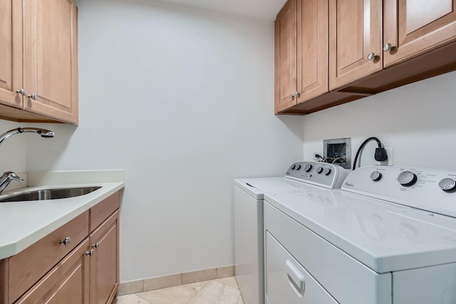 laundry area with cabinet space, baseboards, washer and dryer, and a sink