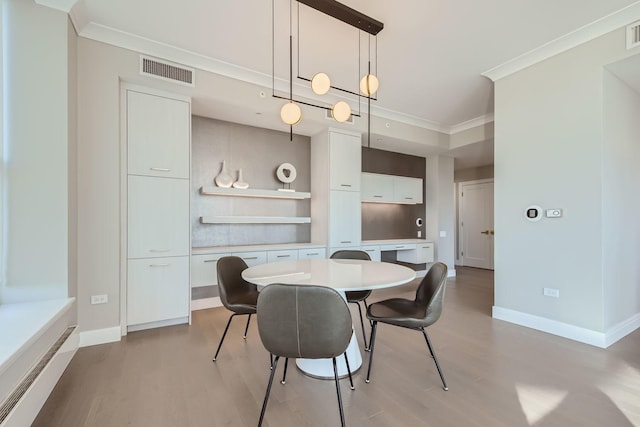 dining area featuring baseboards, light wood-style flooring, visible vents, and crown molding