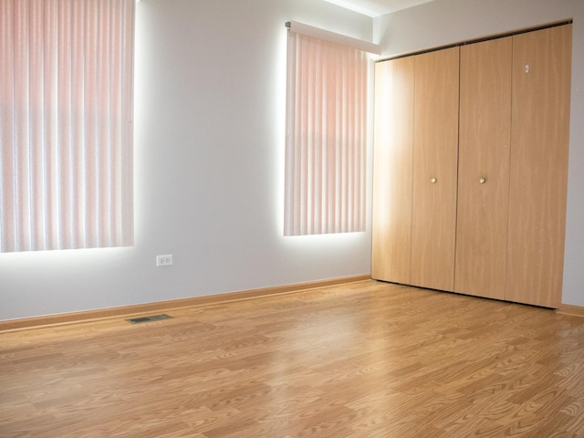 unfurnished bedroom with light wood-style floors, a closet, visible vents, and baseboards