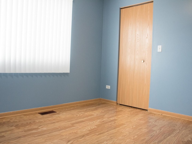 unfurnished bedroom featuring light wood-type flooring, baseboards, visible vents, and a closet