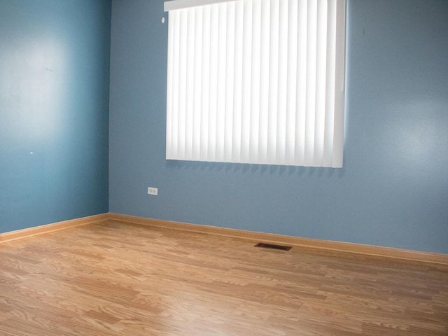 spare room with light wood finished floors, baseboards, and visible vents