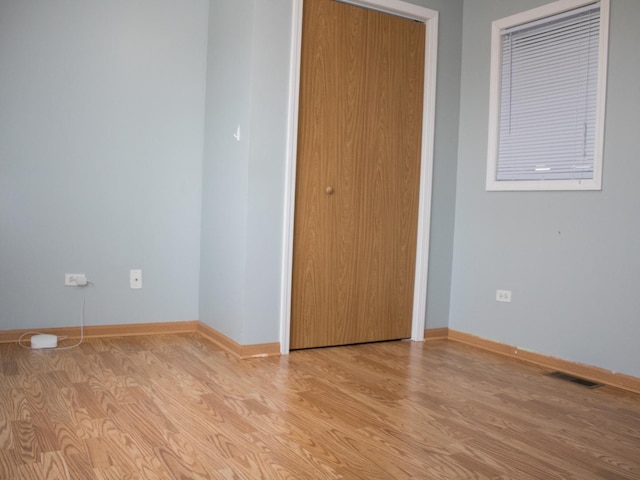 empty room featuring light wood-style floors, visible vents, and baseboards