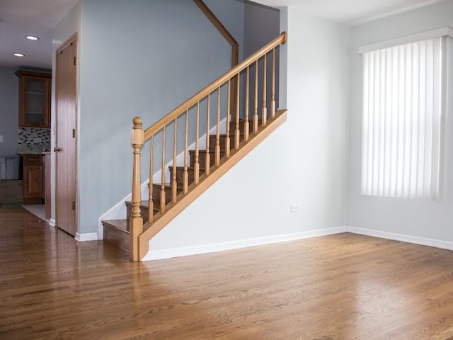 stairway featuring a healthy amount of sunlight, baseboards, and wood finished floors