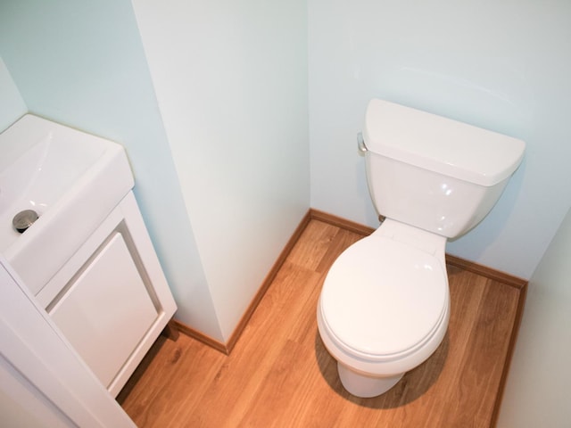 half bathroom featuring baseboards, toilet, and wood finished floors