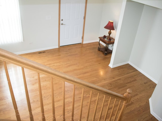 staircase featuring baseboards, visible vents, and wood finished floors