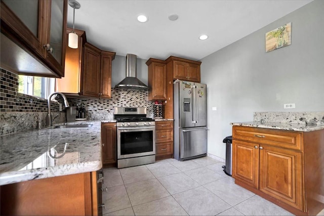 kitchen featuring appliances with stainless steel finishes, brown cabinetry, a sink, and wall chimney exhaust hood