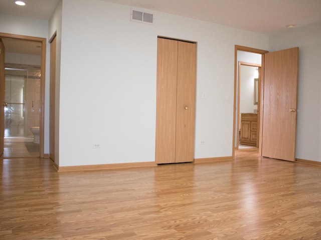 unfurnished bedroom featuring light wood-style floors, baseboards, visible vents, and connected bathroom