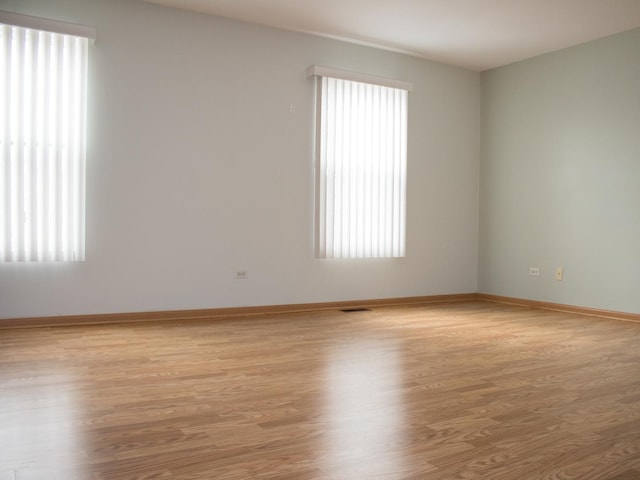 empty room featuring baseboards, visible vents, and light wood finished floors