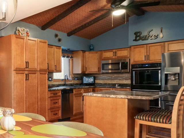 kitchen featuring stainless steel appliances, a kitchen island, dark countertops, and a sink