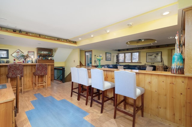 interior space featuring light wood-style floors, recessed lighting, a peninsula, and a breakfast bar area