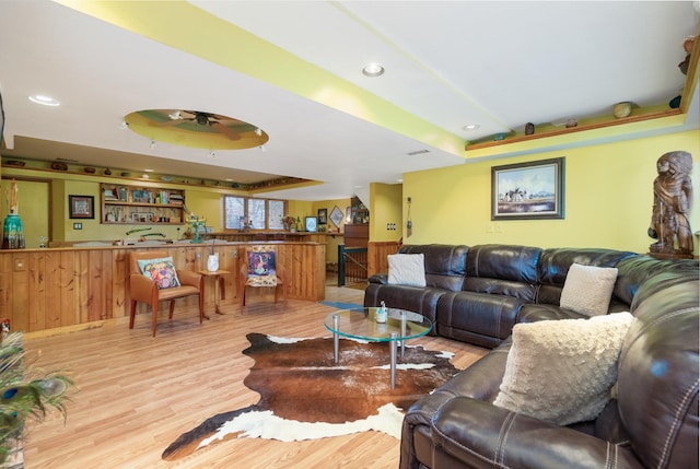 living room with indoor wet bar, light wood finished floors, recessed lighting, a raised ceiling, and ceiling fan