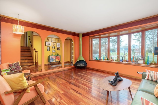 living area featuring a wealth of natural light, stairs, arched walkways, and wood finished floors