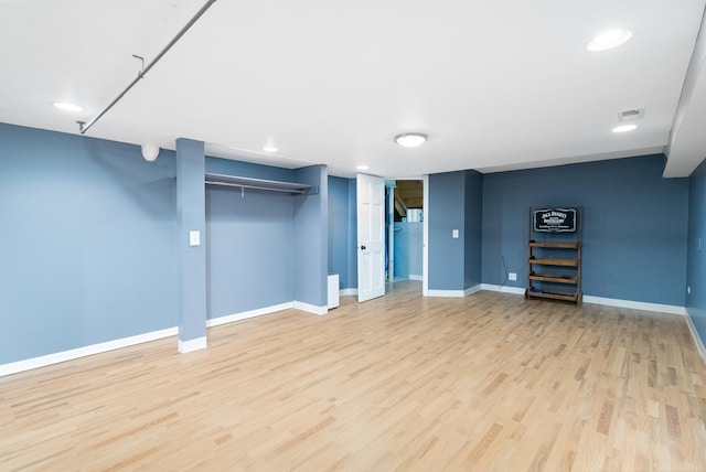 finished below grade area featuring light wood finished floors, visible vents, baseboards, and recessed lighting