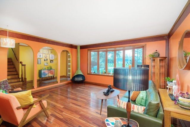 sitting room with arched walkways, stairway, baseboards, and wood finished floors