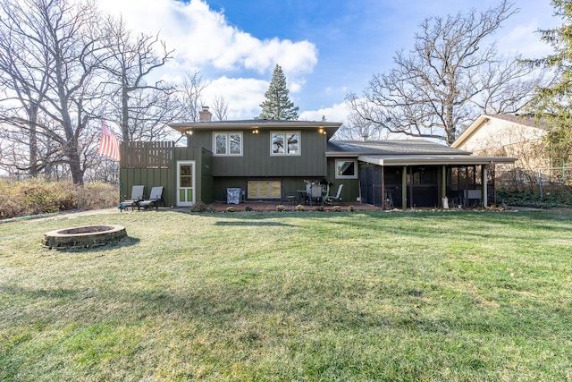 rear view of property with a chimney, a fire pit, and a yard