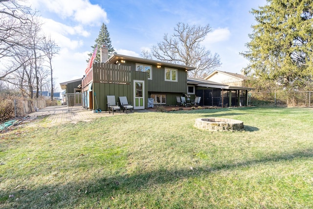 back of house featuring fence private yard, an outdoor fire pit, a chimney, and a lawn