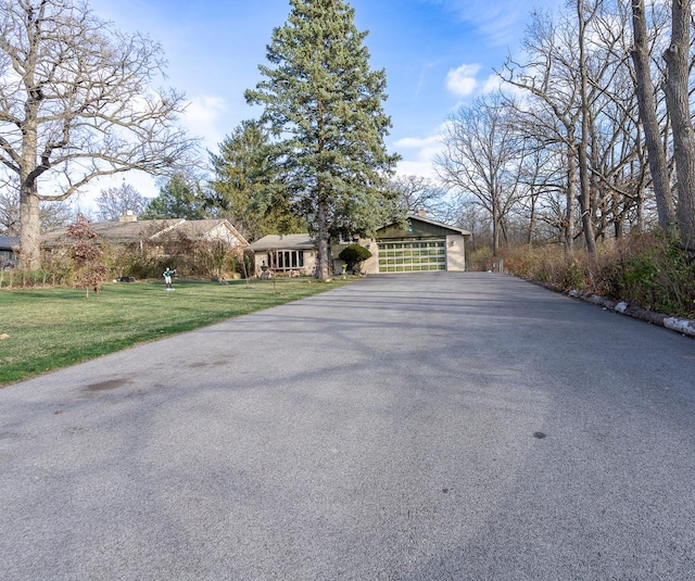 view of front of home featuring a garage, aphalt driveway, and a front yard