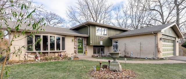 split level home featuring a garage, brick siding, driveway, and a front lawn