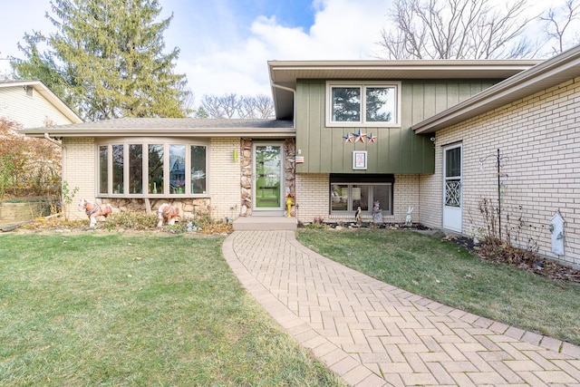 view of exterior entry with a yard and brick siding