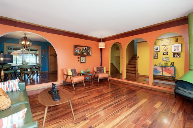 living room featuring arched walkways, stairway, an inviting chandelier, wood finished floors, and baseboards