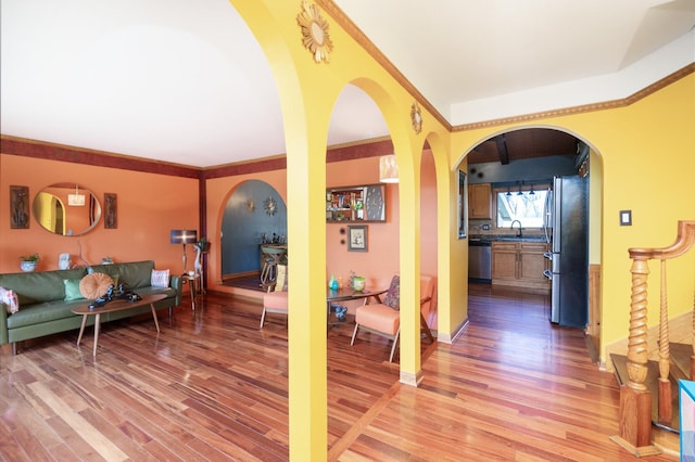 interior space with arched walkways, baseboards, and wood finished floors