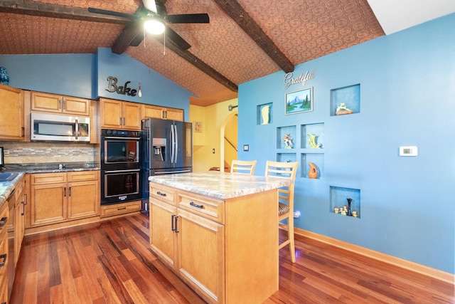 kitchen featuring ceiling fan, dark wood-type flooring, appliances with stainless steel finishes, a center island, and beamed ceiling