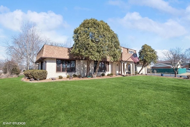 view of front of house featuring a shingled roof, a front lawn, mansard roof, and brick siding