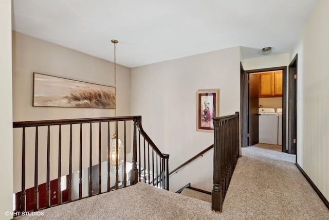 hallway with washer and dryer, carpet, and an upstairs landing