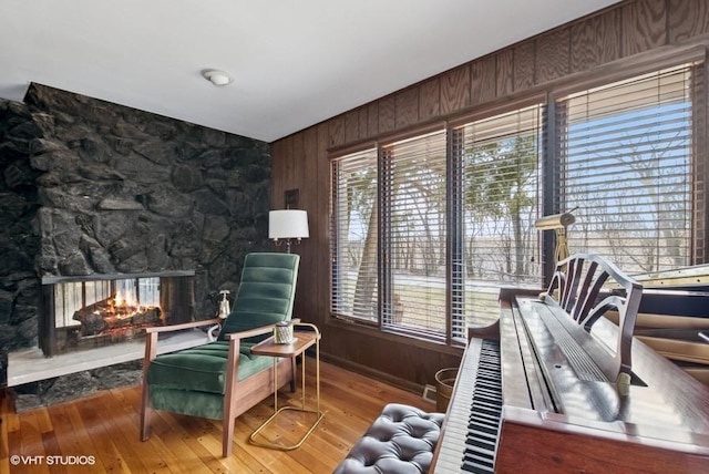 sitting room with wood walls, a fireplace, and wood finished floors