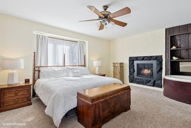 carpeted bedroom featuring a ceiling fan and a glass covered fireplace