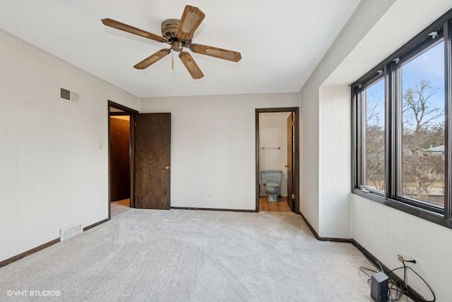 unfurnished bedroom featuring visible vents, baseboards, a ceiling fan, ensuite bathroom, and carpet