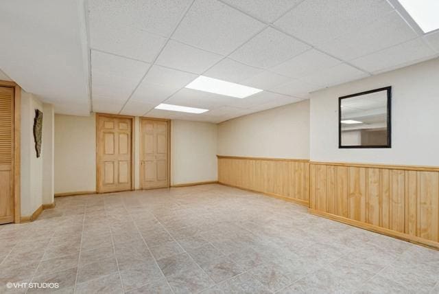 spare room featuring wainscoting, a paneled ceiling, and wooden walls