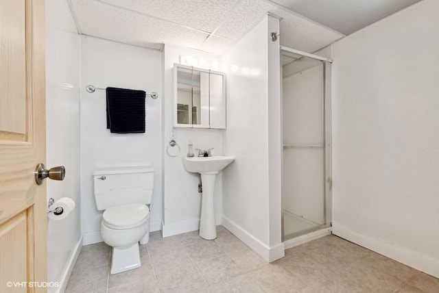 bathroom featuring a paneled ceiling, a shower stall, toilet, and baseboards