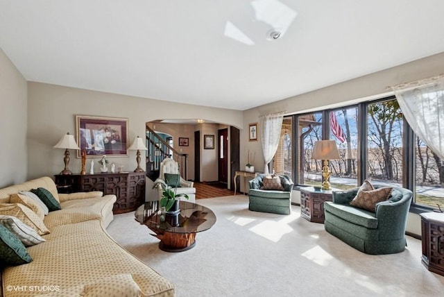 living room with carpet floors, arched walkways, and stairway