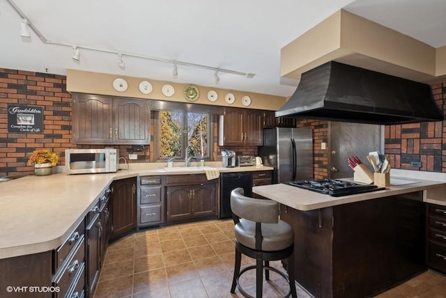 kitchen with light countertops, dark brown cabinets, a peninsula, and black appliances