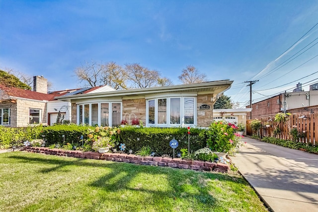 view of front of home with stone siding, a front lawn, and fence