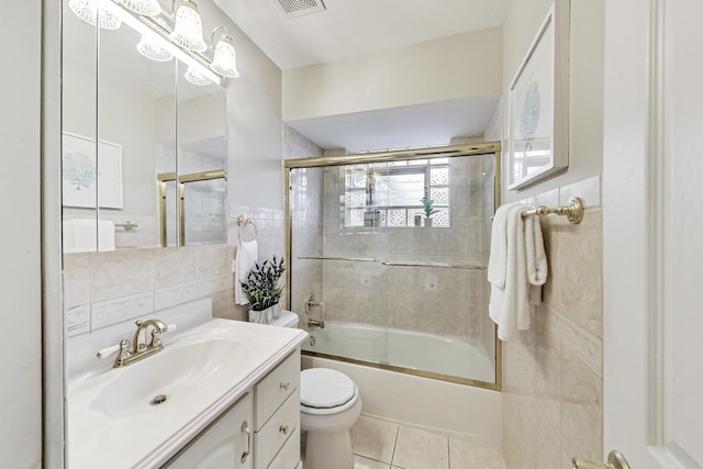 bathroom with tile walls, toilet, enclosed tub / shower combo, vanity, and tile patterned flooring