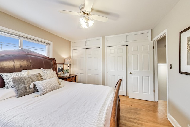 bedroom with ceiling fan, light wood finished floors, baseboards, and multiple closets