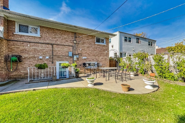 rear view of house with a yard, fence, a patio, and brick siding