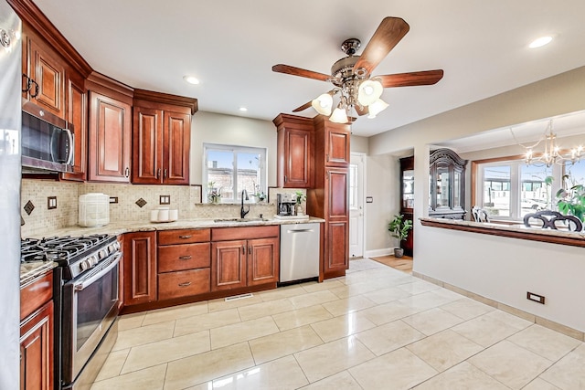 kitchen featuring tasteful backsplash, baseboards, appliances with stainless steel finishes, light stone counters, and a sink